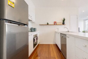 Eine moderne Küche mit Edelstahlgeräten, weißen Schränken und Holzboden.