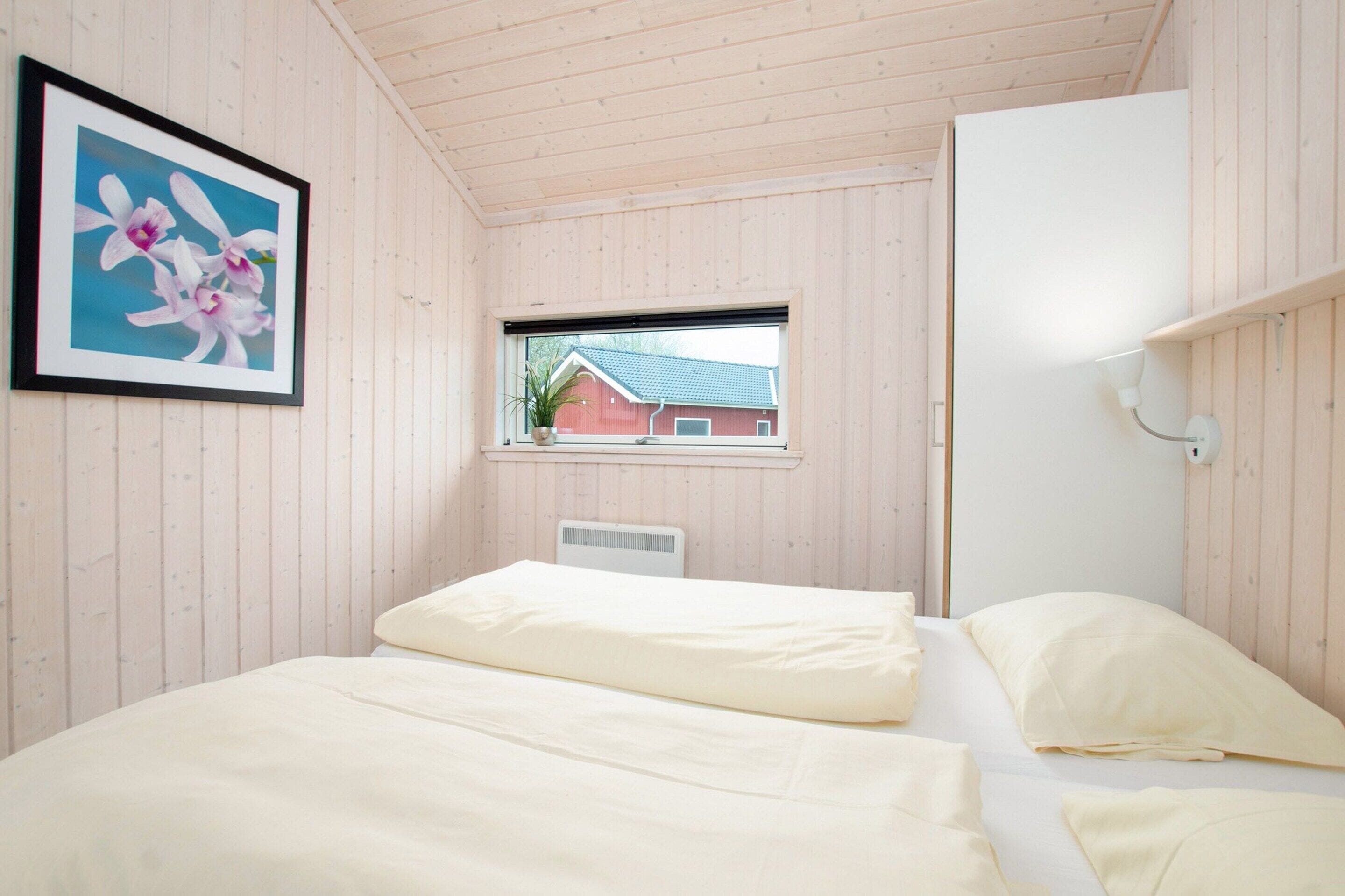 A bedroom with a bed, a window, a radiator, and a framed picture on the wall.