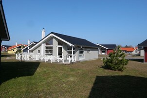 A residential house with a porch, a chimney, and a small lawn.