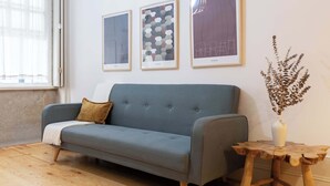 A room with a grey sofa, a wooden side table with a vase, and three framed artworks on the wall. - Historic Se Apartment Prime Location by HostWise (Sé)