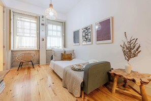 Um quarto acolhedor com uma cama, uma cadeira, uma mesinha e um candeeiro suspenso.