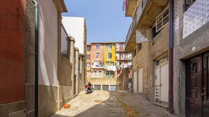 A narrow street with buildings on either side, a motorcycle parked on the side, and laundry hanging from balconies. - Historic Se Apartment Prime Location by HostWise (Sé)