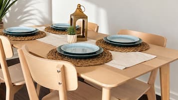 A dining area with a wooden table, six chairs, and decorative plates on woven placemats.