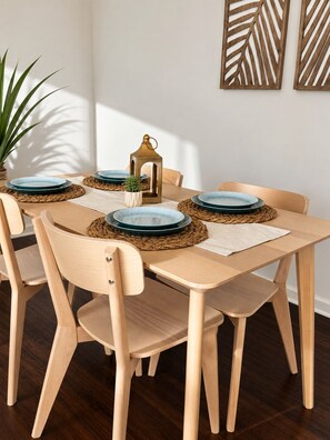 A dining area with a wooden table, six chairs, and decorative plates on woven placemats.