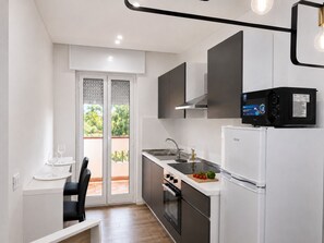 A compact kitchen with a built-in oven, a refrigerator, and a sink. - Riace Mare – Premium | 100 m from the beach (Riace Marina)