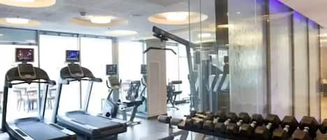 Uma academia com esteiras, halteres e equipamentos de ginástica.