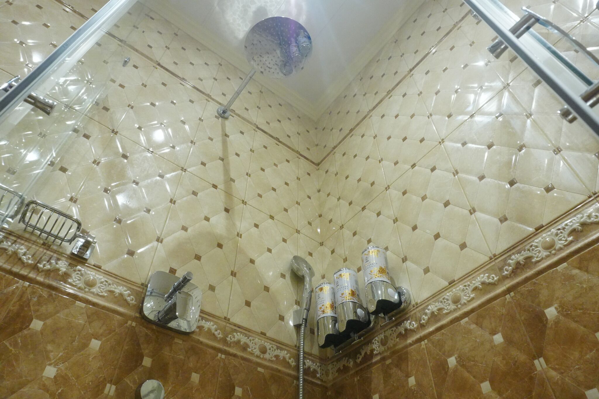 A bathroom with a tiled ceiling, a shower area, and a marble floor.