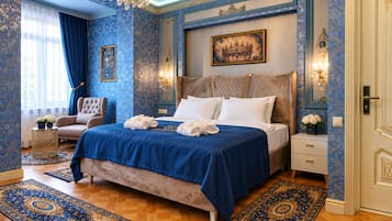 Un dormitorio con una cama grande, una zona de estar con una silla y una araña.