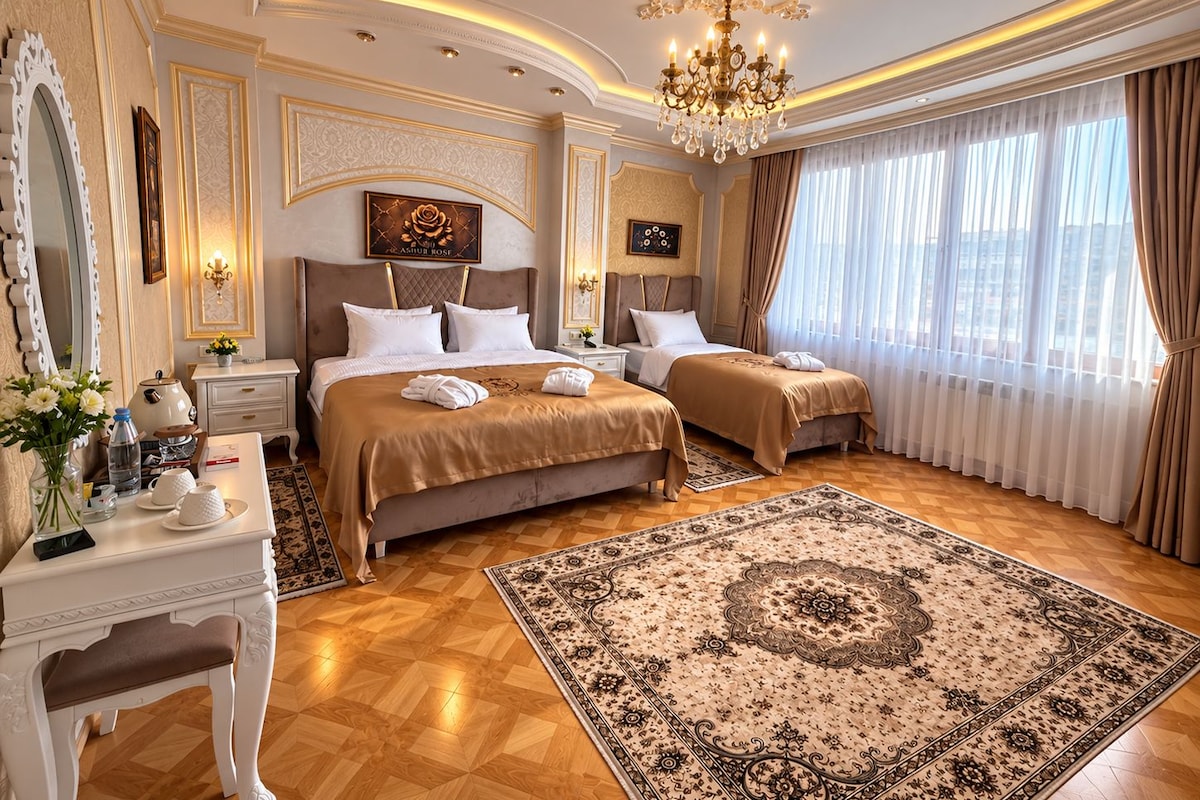 Habitación de hotel con dos camas, un candelabro, un tapete grande y vistas a la ciudad.
