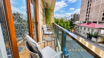 A balcony with a view of the city, furnished with chairs and a table.