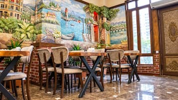 Un restaurante con un mural de una escena costera, paredes de ladrillo y piso de baldosas.