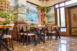 Un restaurante con un mural de una escena costera, paredes de ladrillo y piso de baldosas.