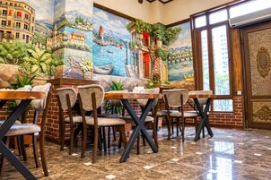 Un restaurante con un mural de una escena costera, paredes de ladrillo y piso de baldosas.