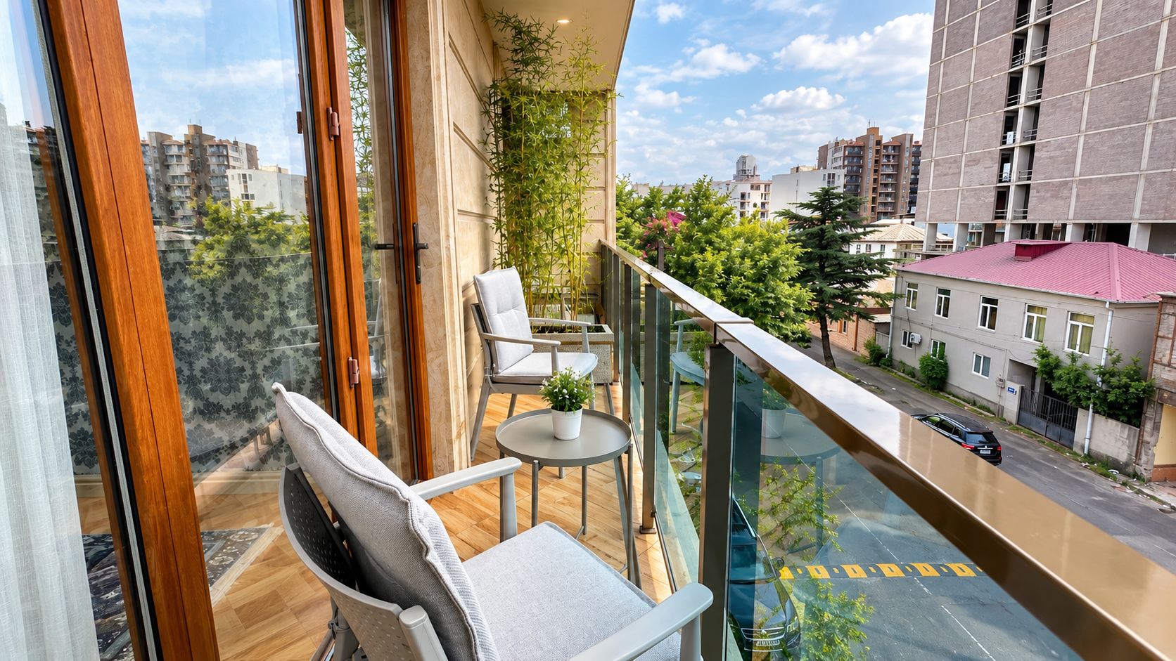 Ein Balkon mit Blick auf eine Stadtlandschaft, möbliert mit Stühlen und einem kleinen Tisch.