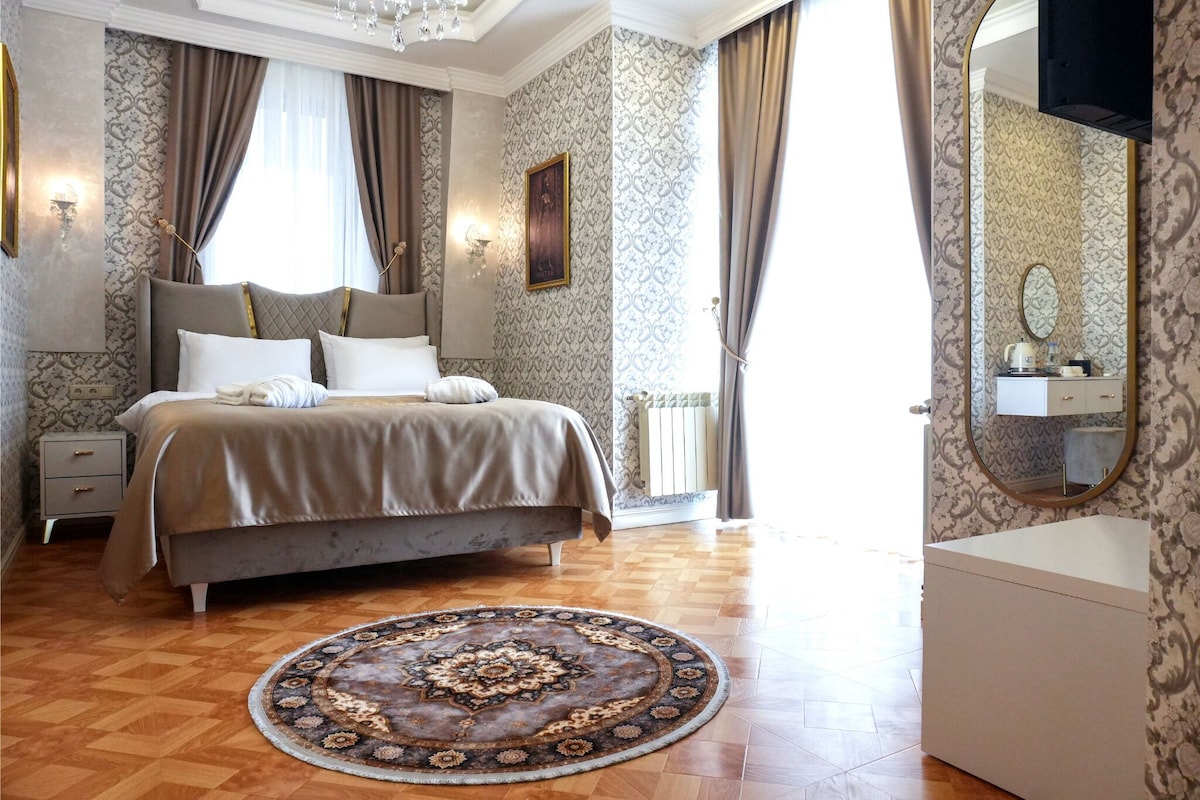 A bedroom with a bed, bedside tables, a round rug, a dresser, and a mirror.