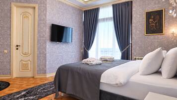 Une chambre d’hôtel comprenant un lit, un téléviseur à écran plat, une porte ornée de panneaux décoratifs et un tapis à motifs.
