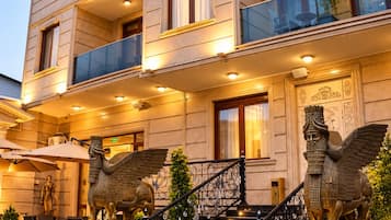 A multi-story hotel with balconies, a grand staircase, and decorative statues.