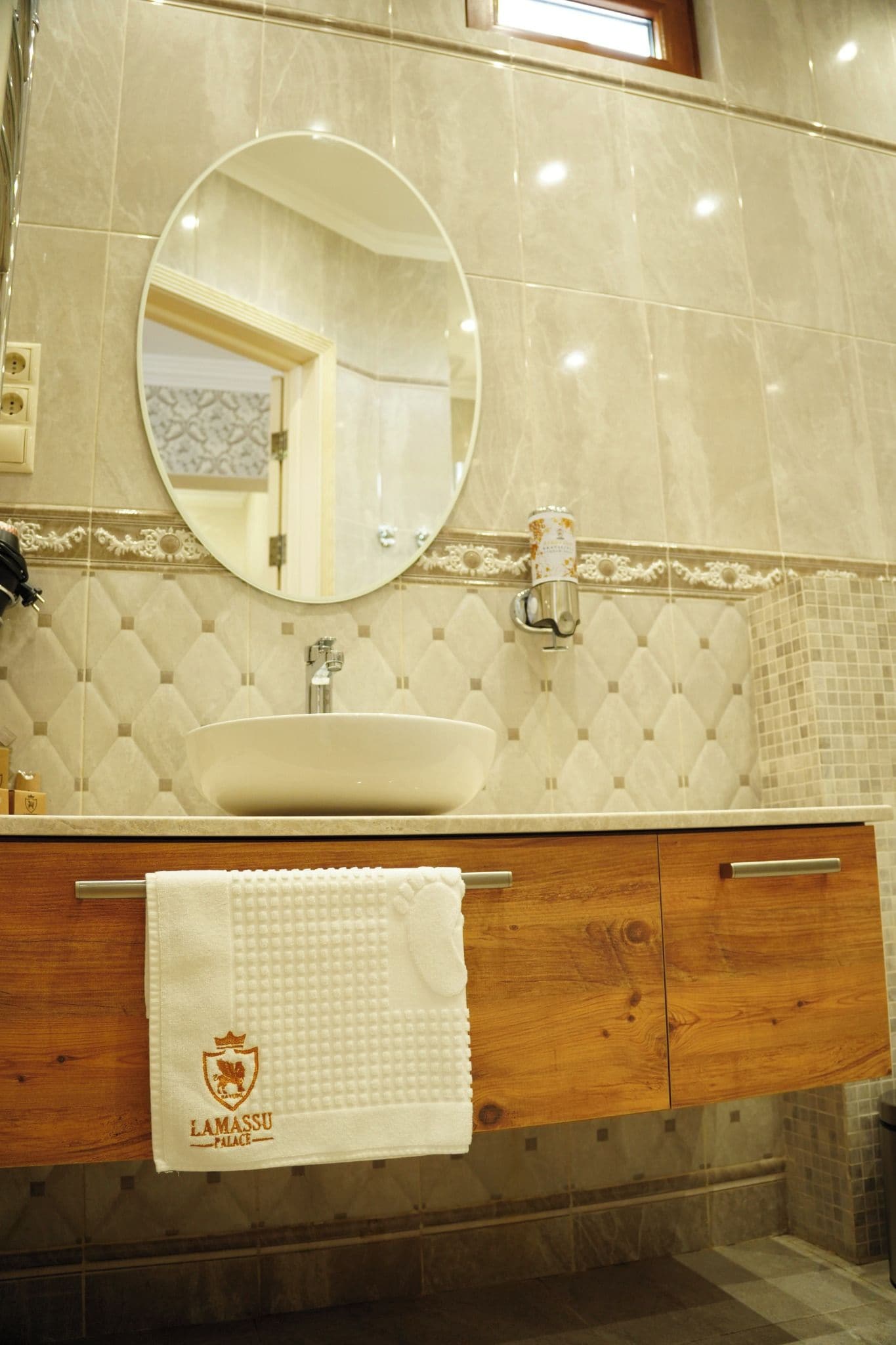 A bathroom with a round mirror, a sink, and a towel hanging on a wooden cabinet.