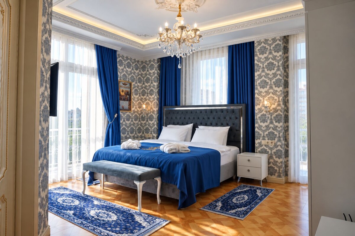 Una habitación de hotel con una cama grande, un banco, una mesita de noche y un candelabro.