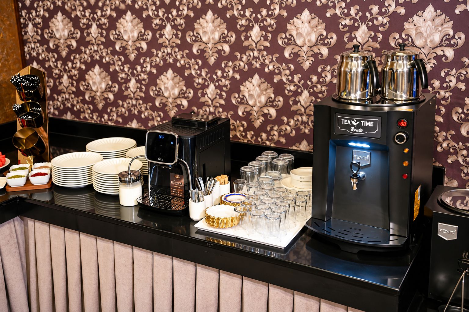 Una estación de café con una máquina de café, dispensador de té y diversas tazas y platos.