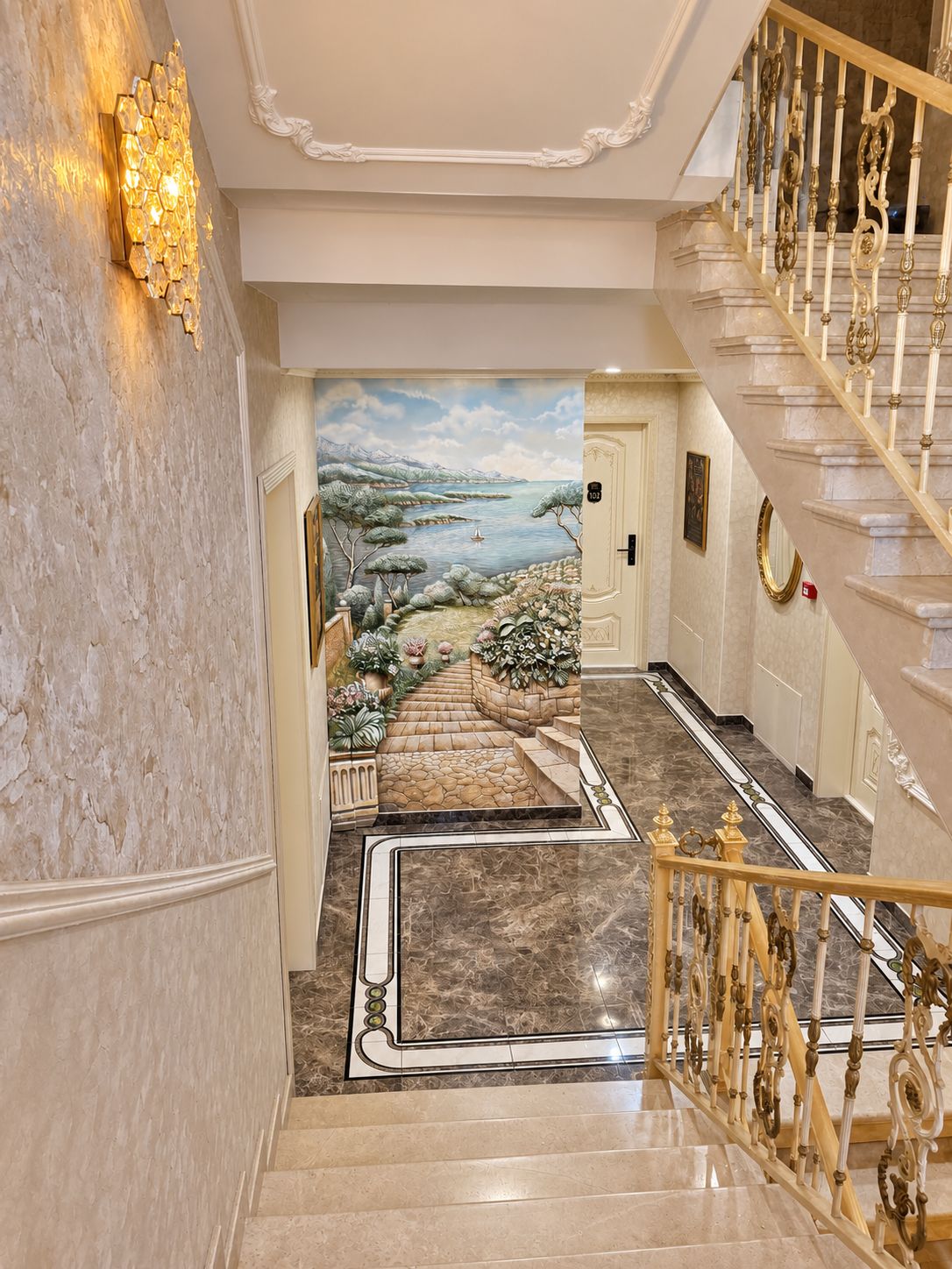 A grand staircase with ornate railings leading to a door with a number plaque.