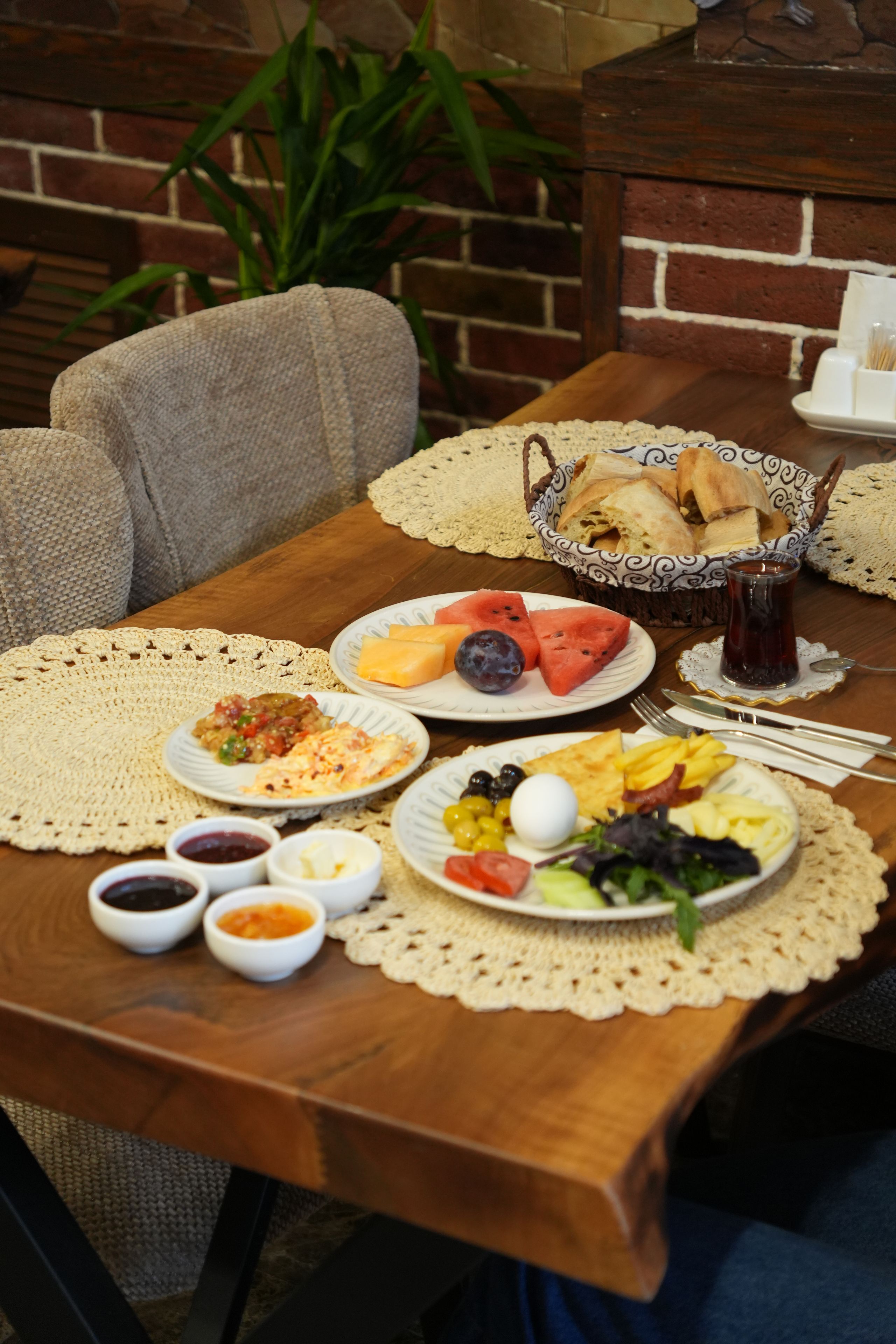 A table set with various dishes including bread, fruits, and vegetables, suggesting a meal setting.