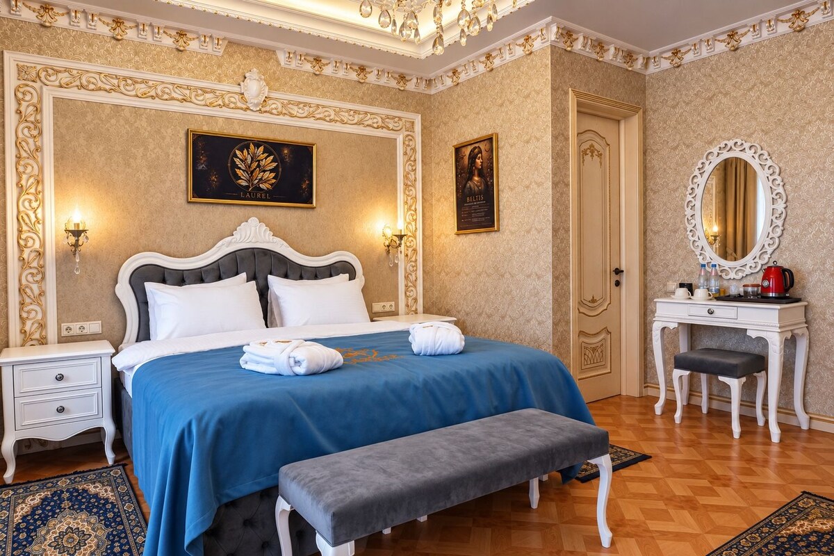 Una habitación de hotel con una cama grande, un tocador con espejo y una banca.
