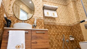 Un baño con un espejo redondo, un lavabo, un perchero con toallas y una ducha.
