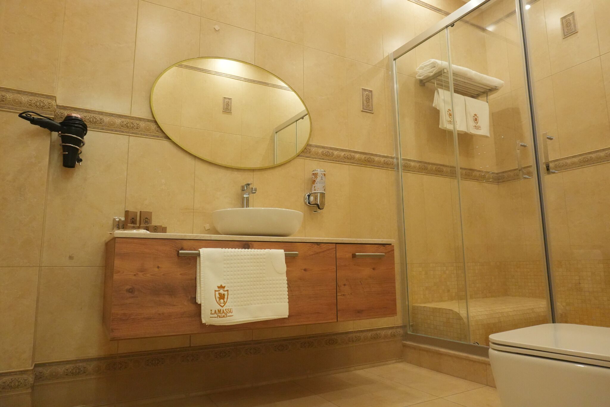A bathroom with a round mirror, a sink, a glass shower enclosure, and a toilet.