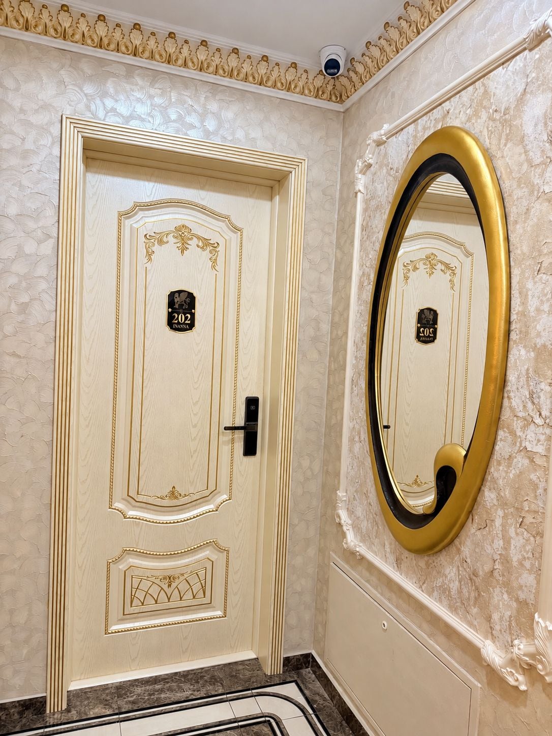 A room with a door marked '202' and a large mirror with a gold frame.
