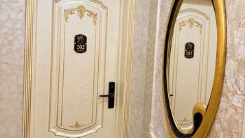 A room with a door marked '202' and a large mirror with a gold frame.