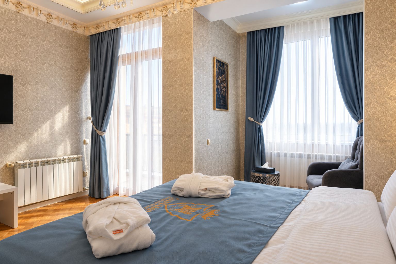 Una habitación de hotel con cama, una silla, escritorio y radiador.