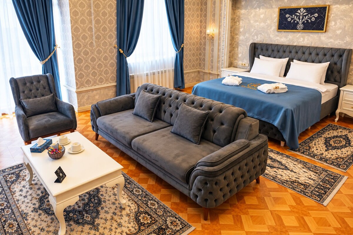 Una habitación de hotel con una cama, dos sofás, una mesita y una alfombra estampada.