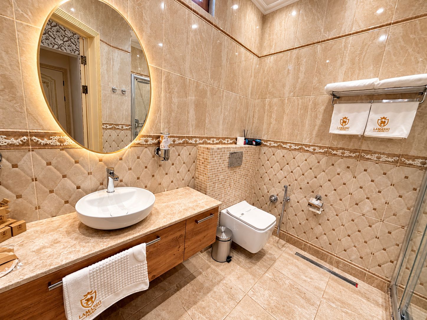 Un baño moderno con un espejo redondo, un lavabo, un bidé y un perchero para toallas.