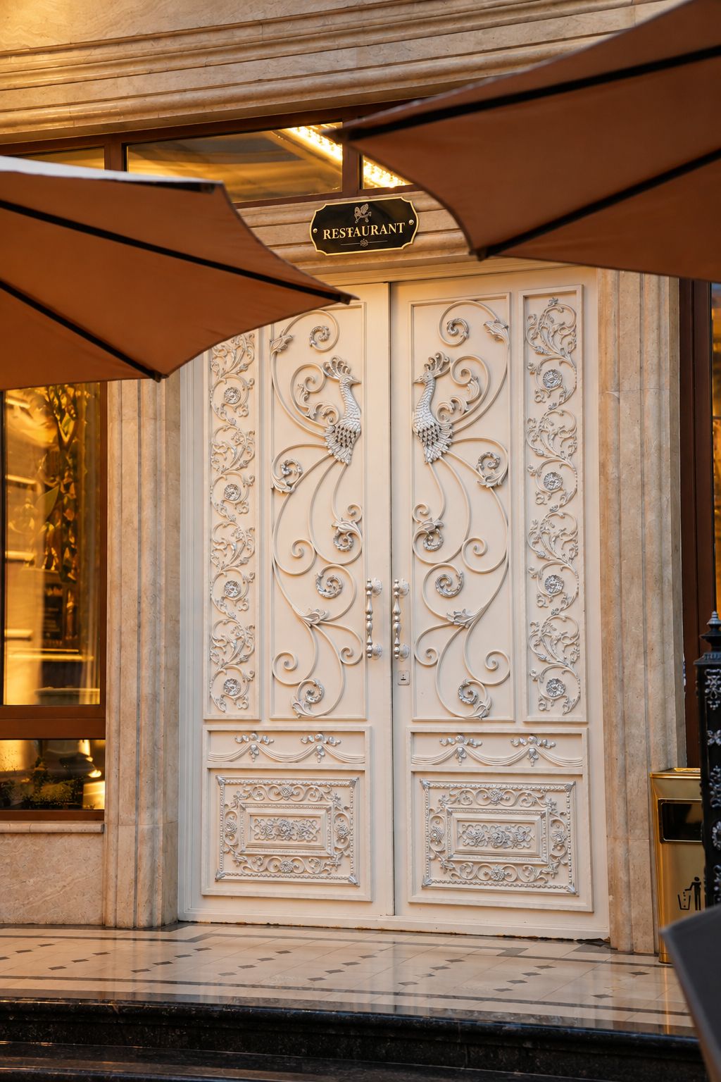 Une porte à deux battants ornée de sculptures complexes, et une enseigne au-dessus indiquant « RESTAURANT ».