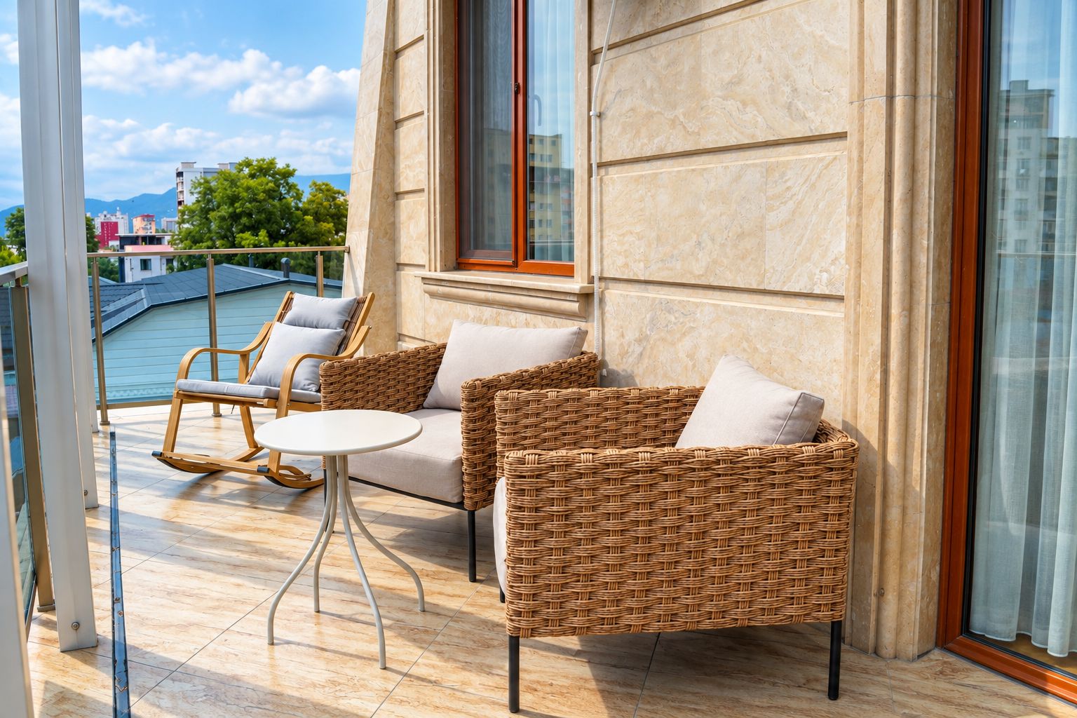 A balcony with wicker furniture, a small round table, and a view of the cityscape.