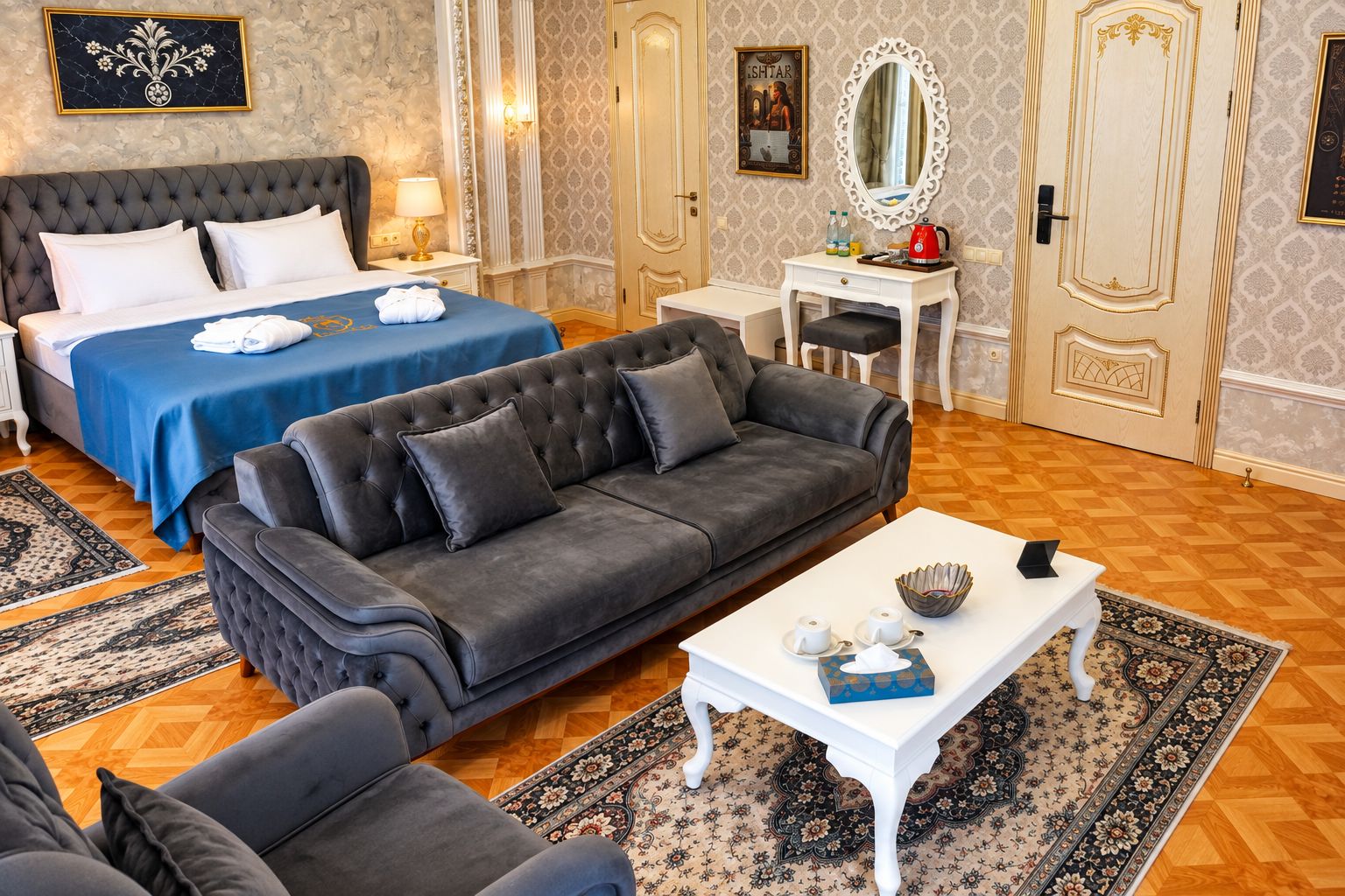 A hotel room with a large bed, a sofa, a small table, and a desk.
