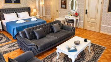 A hotel room with a large bed, a sofa, a small table, and a desk.