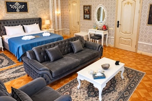 Una habitación de hotel con una cama grande, un sofá, una mesita y un escritorio.