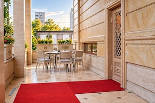 Un pasillo de hotel con alfombra roja, una zona de comedor con mesas y sillas, y una puerta decorativa.