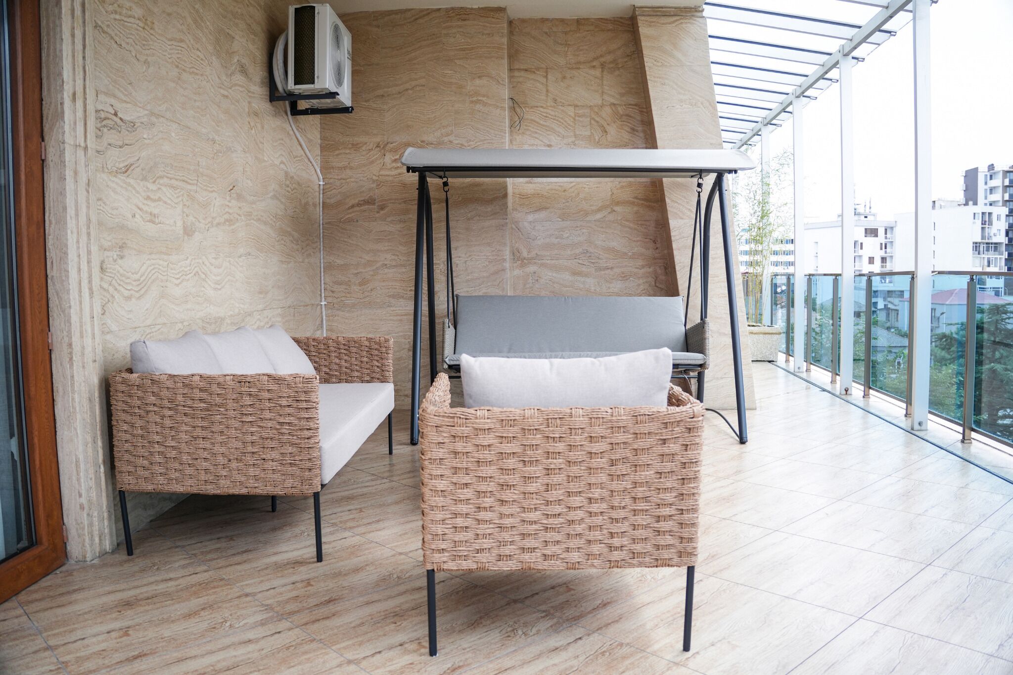 Ein Balkon mit Korbmöbeln, einem Deckenventilator und Blick auf Gebäude.