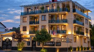 Un hotel a più piani con balconi, un cartello che indica che si tratta di un hotel di lusso con suite, e un ingresso ben illuminato.
