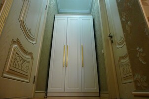 Un armario blanco con dos pomos, flanqueado por molduras decorativas y una pared con diseño.