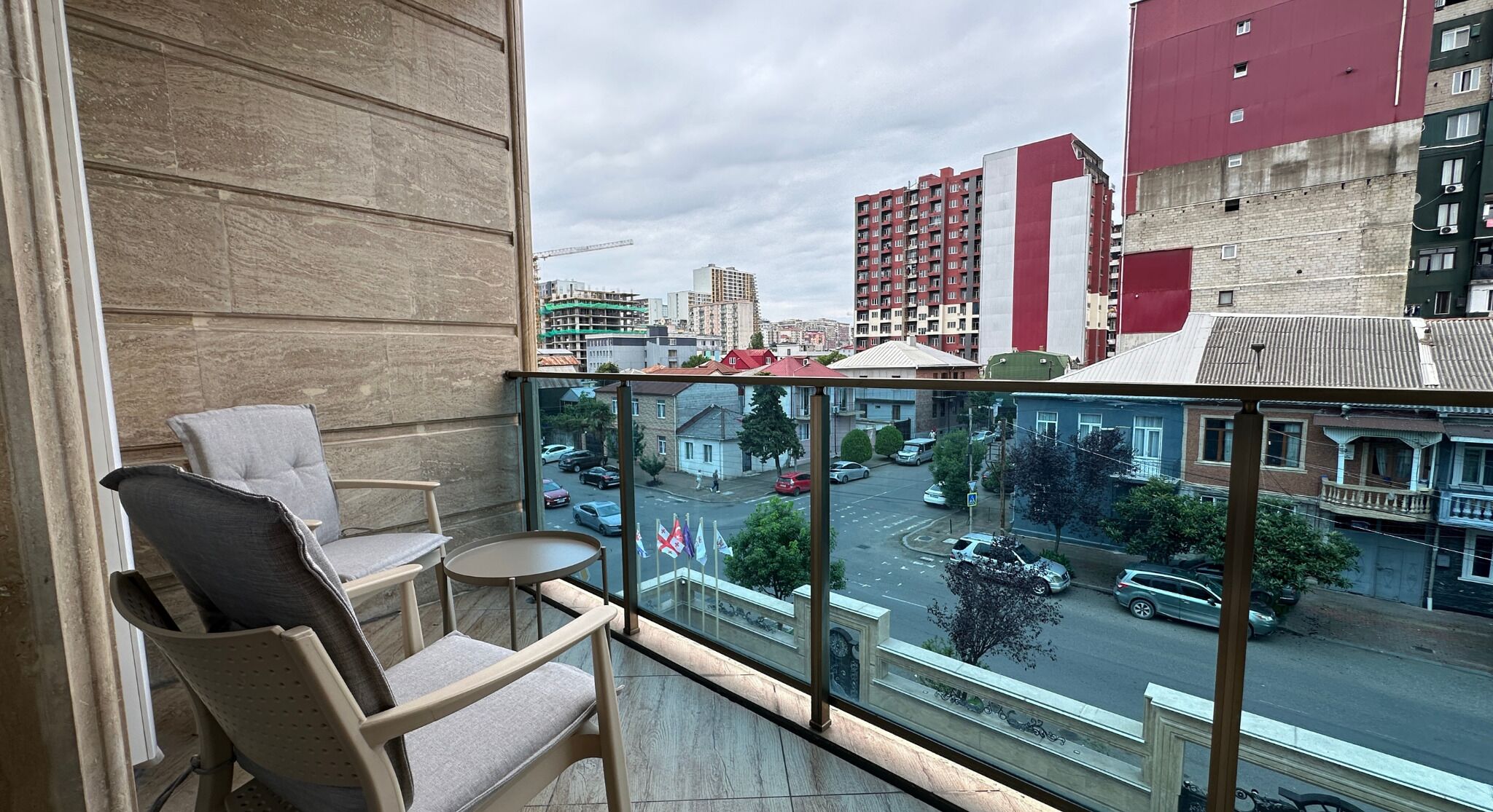 A balcony with a view of a cityscape, including buildings and a street.