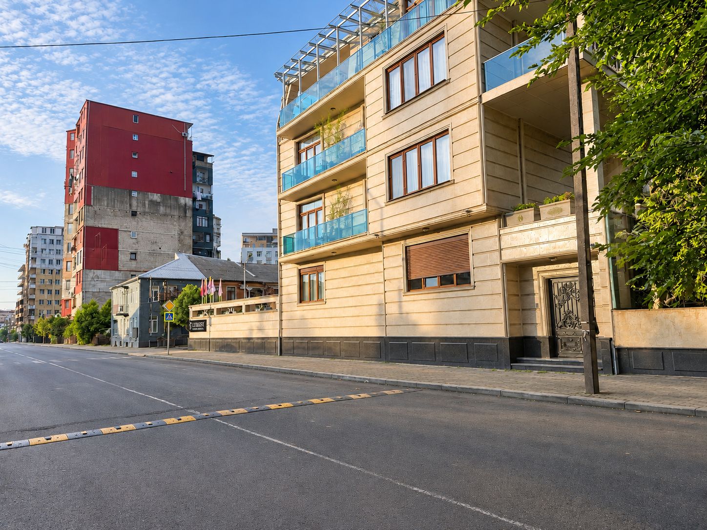A multi-story building with balconies, a street in front, and other buildings in the background.