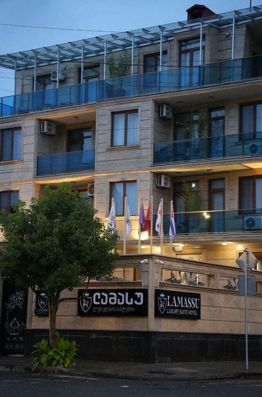 A multi-story building with balconies, air conditioning units, and flags.