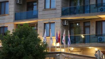 A multi-story building with balconies, air conditioning units, and flags.