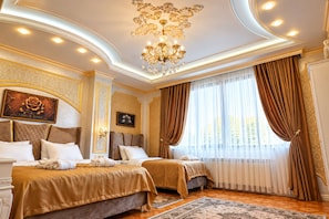 Una lujosa habitación de hotel con dos camas, un candelabro y un ventanal con cortinas.