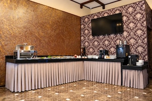 Montaje de bufé con una parrilla, estación de café y un televisor de pantalla plana en la pared.