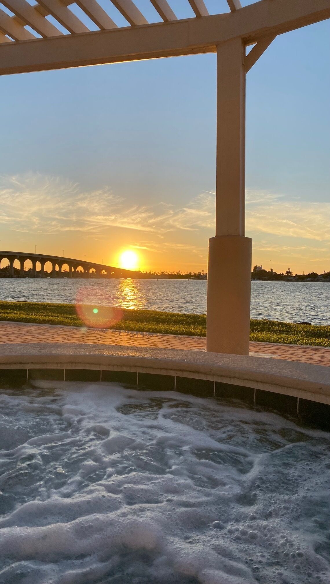A water feature with a bridge in the background during sunset.